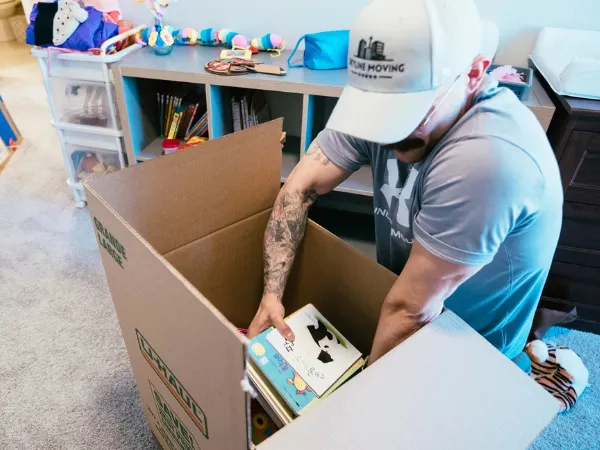 Skyline Moving Services helps pack books into a large cardboard box for relocation