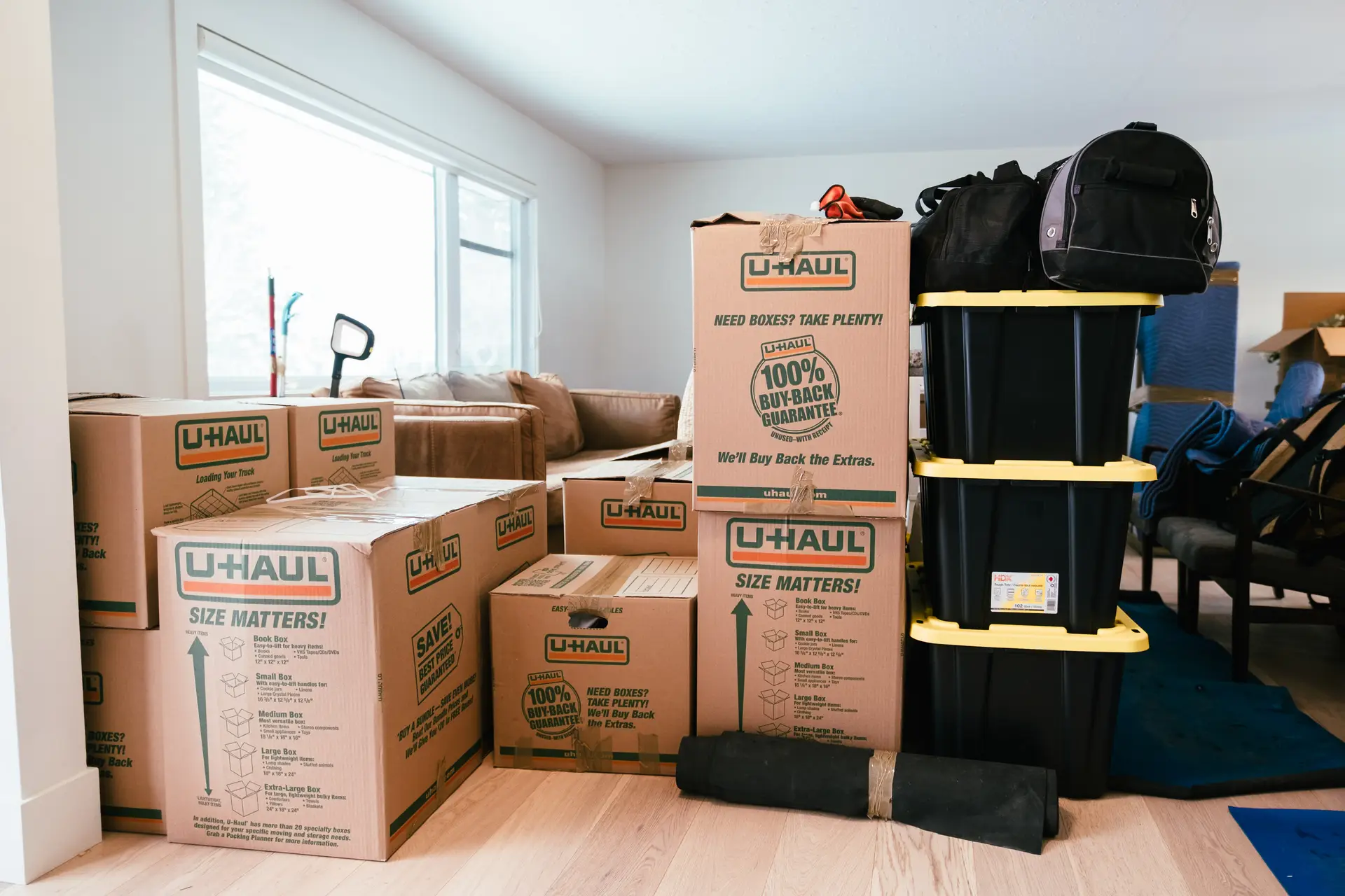 A room filled with stacked moving boxes and storage bins, indicating a recent move