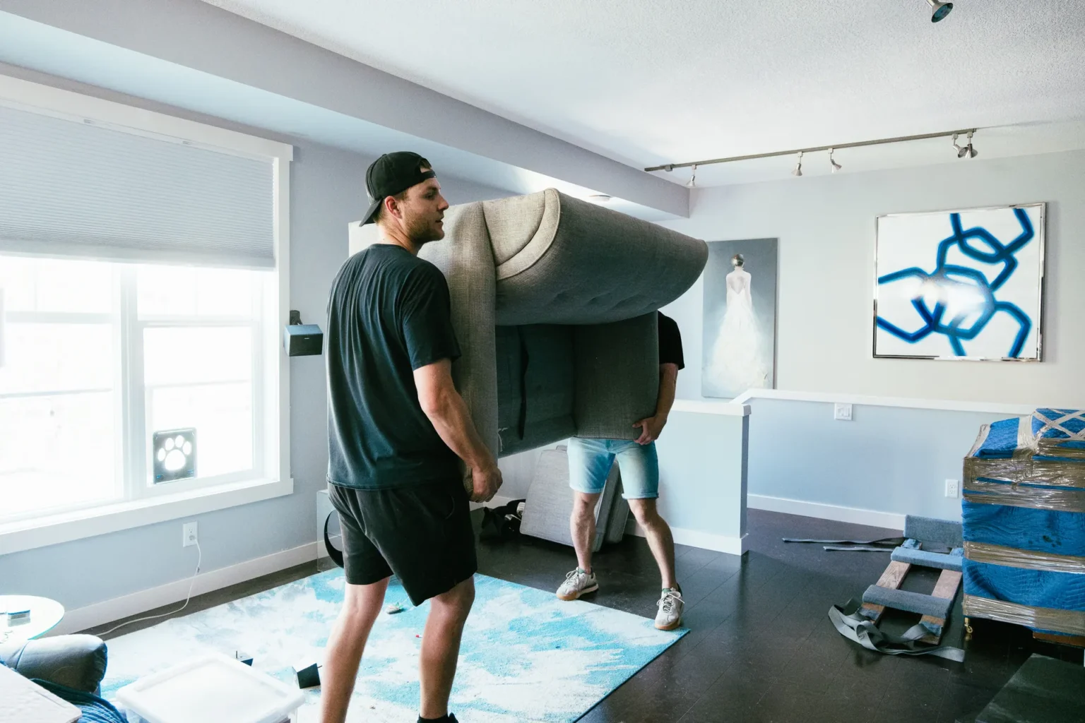 Professional Furniture Movers Calgary wrapping a leather sofa in protective moving blankets.