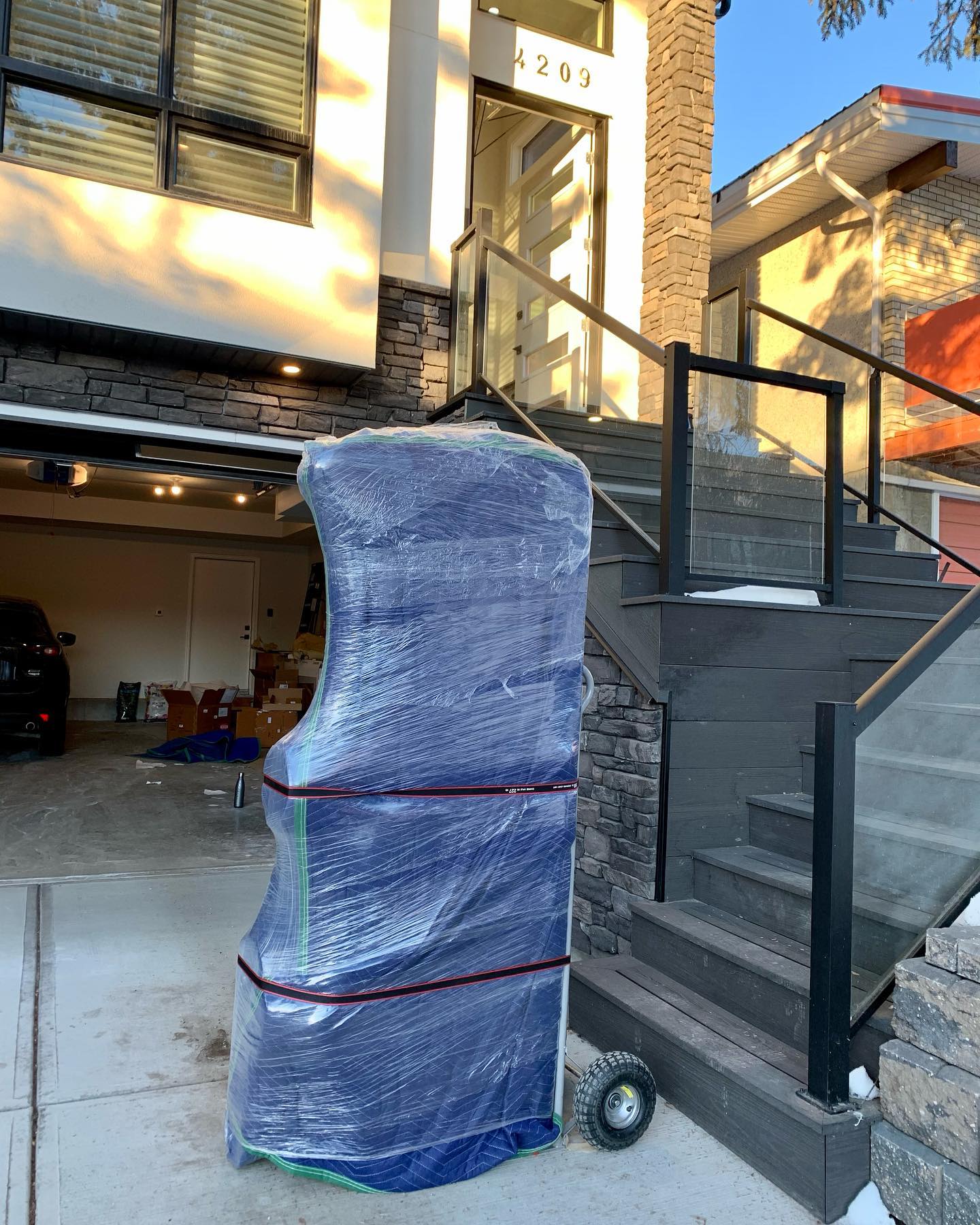 A large object wrapped in plastic is being moved up stairs